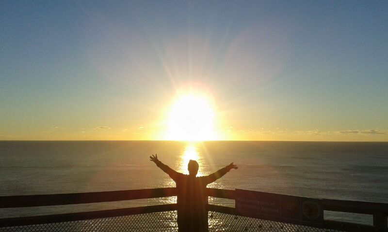 Die Welt vor einem Sonnenuntergang über dem Meer umarmen